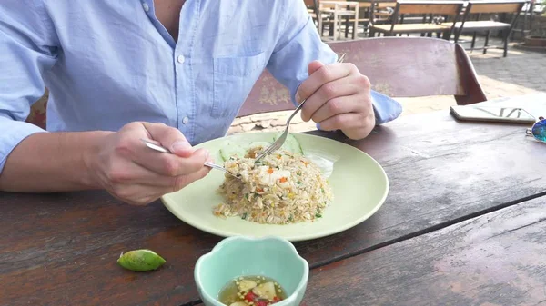 Close-up. homem espreme suco de limão em um prato com arroz de Jasmim frito com ovo e camarões, decorado com pepino . — Fotografia de Stock