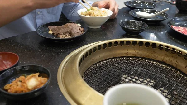 Churrasqueira coreana. as pessoas cozinham e comem pratos cozidos em um churrasco coreano em um restaurante. close-up . — Fotografia de Stock