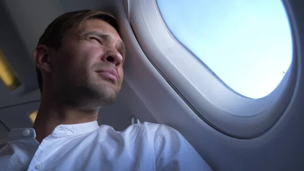 Крупным планом. портрет красивого молодого человека, смотрящего в окно самолета во время полета . — стоковое фото