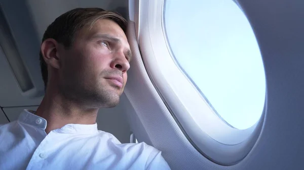Крупным планом. портрет красивого молодого человека, смотрящего в окно самолета во время полета . — стоковое фото