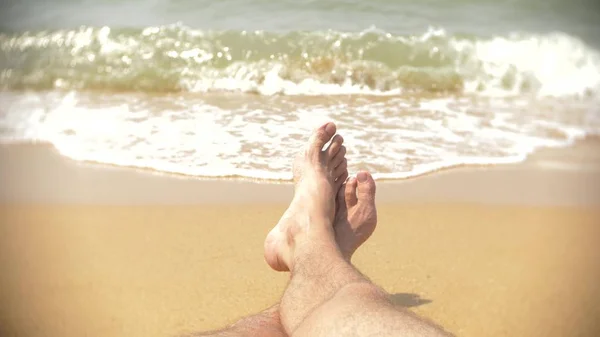 Mens legs on the beach on the background of a wave of — Stock Photo, Image