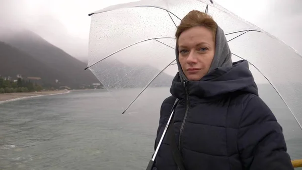 Eine Frau unter einem Regenschirm am Meer im Regen, an einem regnerischen Herbsttag — Stockfoto