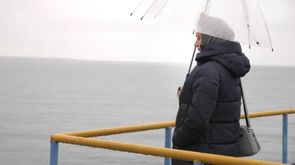 Une femme sous un parapluie au bord de la mer sous la pluie, un jour pluvieux d'automne — Photo