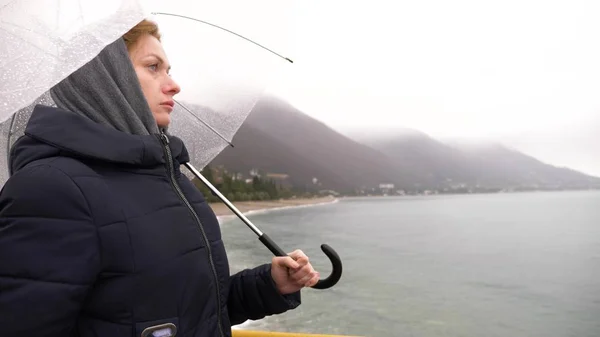 Seorang wanita di bawah payung di laut dalam hujan, pada hari hujan, musim gugur — Stok Foto