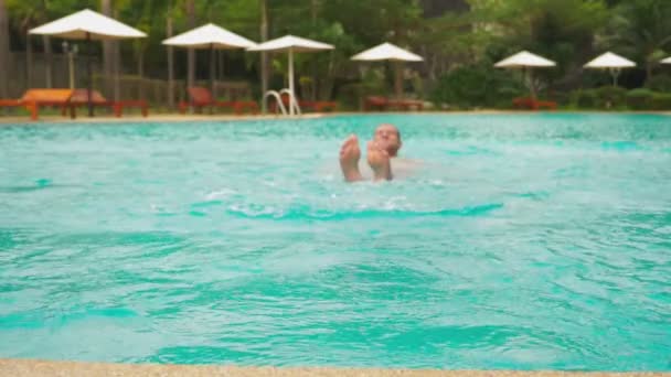 Радостный молодой красивый мужчина, прыгающий в бассейн, отдыхающий в отеле. летние каникулы — стоковое видео