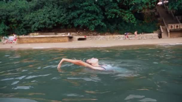 Happy teen girl playing in the sea. girl happily frolics on the beach. Summer vacation and active lifestyle concept — Stock Video