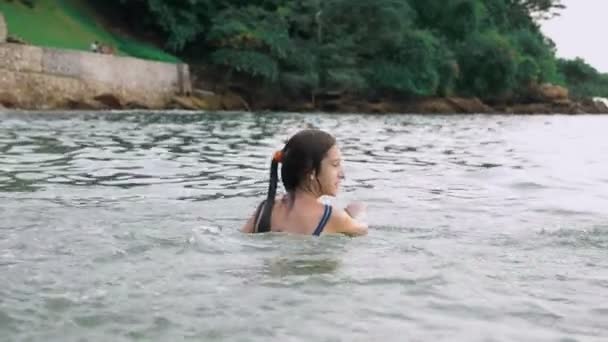 Счастливая девочка-подросток, играющая в море. Девушка счастливо фролики на пляже. Летние каникулы и активный образ жизни — стоковое видео