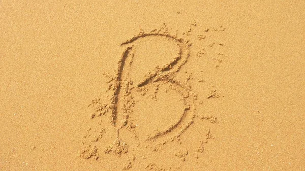海の波は、砂に書いた銘刻文字を消去します。上面図、文字 b — ストック写真
