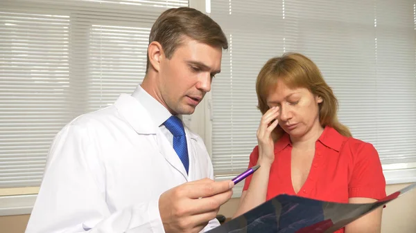 Läkare samråd. läkaren gör bekant patienten med resultaten av Mr, röntgen. resultaten av magnetisk terapi på filmen — Stockfoto