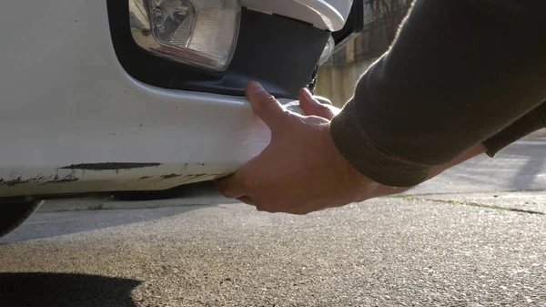 A olhar para um veículo danificado. homem inspeciona danos no carro após um acidente — Fotografia de Stock