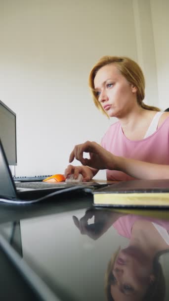 Belle jeune femme travaillant sur un ordinateur portable et un ordinateur tout en étant assis à un bureau . — Video