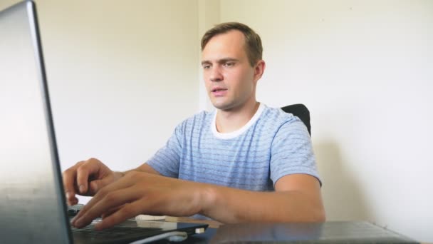 Un uomo seduto a una scrivania a casa, che lavora a casa laptop . — Video Stock