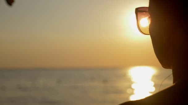 Schöner sonniger Sonnenuntergang am Meer. Blick durch eine Sonnenbrille. Frau mit Sonnenbrille blickt auf den Sonnenuntergang am Meer — Stockvideo