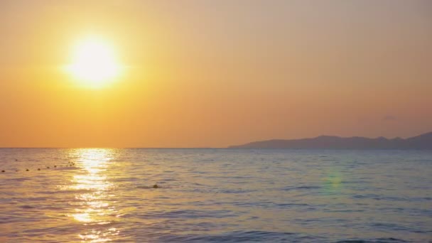美丽的日落在海上。晚上有人在海里游泳 — 图库视频影像