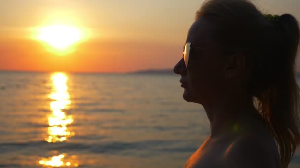 Belo pôr do sol ensolarado no mar. vista através de óculos de sol. mulher em óculos de sol olha para o pôr do sol no mar — Vídeo de Stock