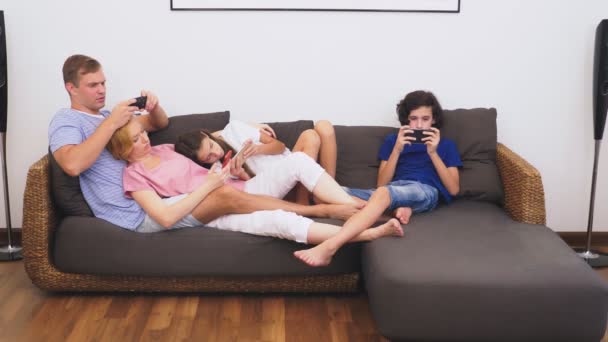 Charmante famille, maman, papa, fille et fils regardent la télévision dans le salon ensemble, tout le monde regarde dans son téléphone — Video