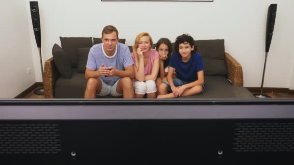 Familia encantadora, mamá, papá, hija e hijo están viendo la televisión en la sala de estar juntos — Vídeos de Stock