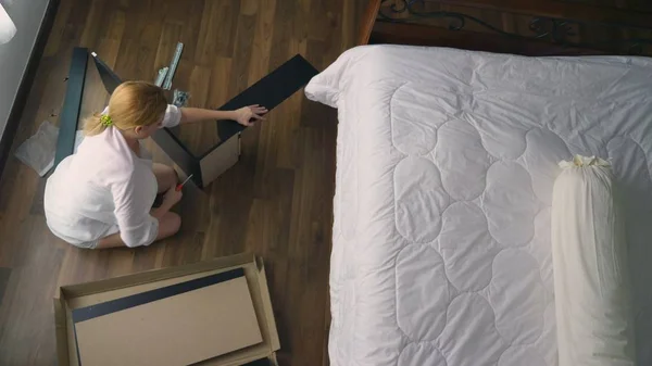 Assembling furniture at home, a housewife assembles a computer desk using hand tools. — Stock Photo, Image