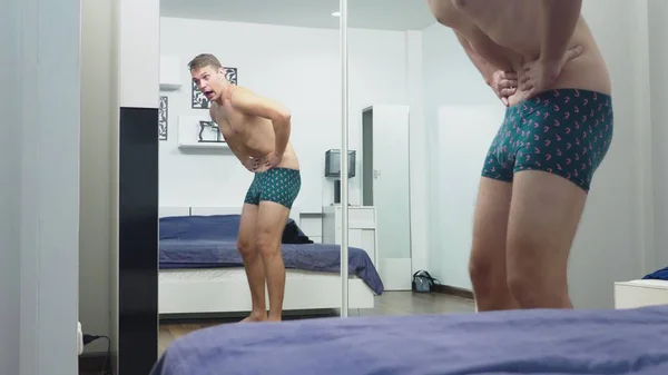 Genç adam yatak odasında bir ayna önünde kaslarını kontrol — Stok fotoğraf