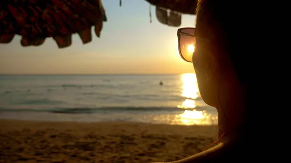 Belo pôr do sol ensolarado no mar. vista através de óculos de sol. mulher em óculos de sol olha para o pôr do sol no mar — Fotografia de Stock