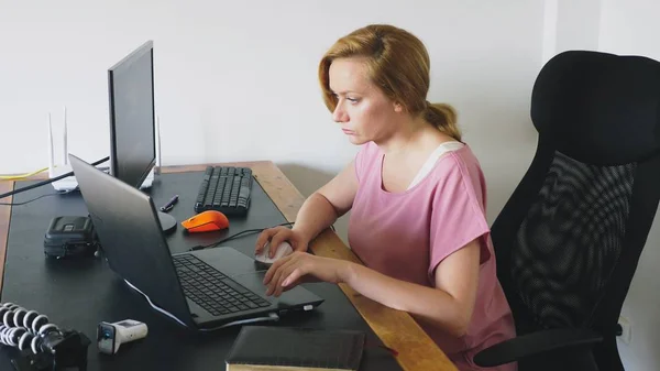Bir masada otururken bir dizüstü bilgisayar ve bilgisayar üzerinde çalışan güzel genç kadın. — Stok fotoğraf