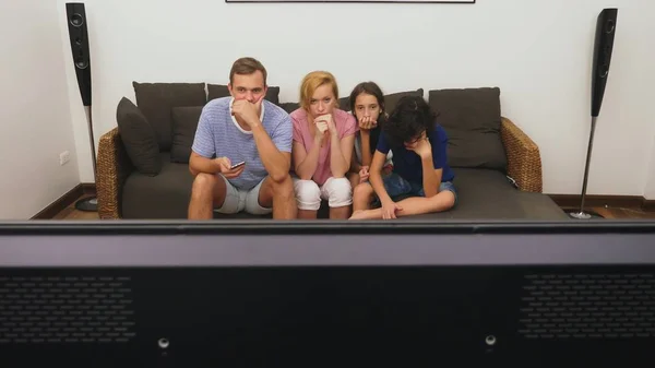 Familia encantadora, mamá, papá, hija e hijo están viendo la televisión en la sala de estar juntos — Foto de Stock