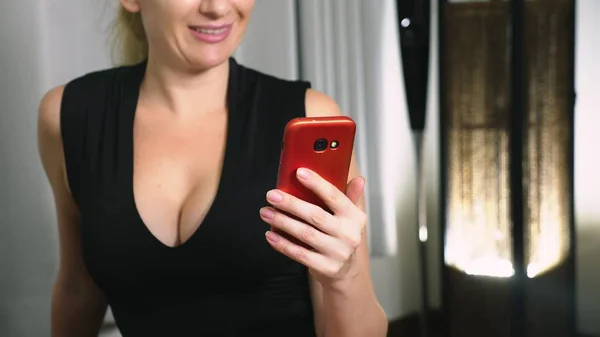 Mulher flerta falando em comunicação de vídeo a partir de seu smartphone. Uma mulher envia um beijo online durante uma chamada de vídeo usando um smartphone . — Fotografia de Stock