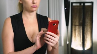 Akşam ve dokunmatik ekranlı akıllı telefon kullanan genç ciddi kadın portresi.