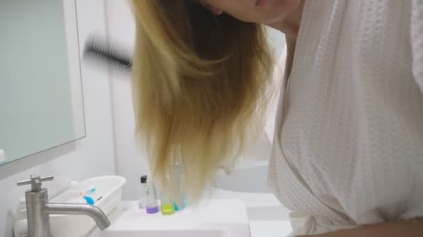 Haj egészségét, haj veszteség koncepció. Fésülködő lány szőke nő sérült száraz haj a fürdőszobában — Stock videók