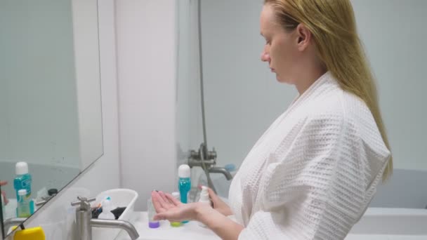 Face care koncept. Kvinna tillämpa kosmetiska lotion för att ta hand om huden i badrummet. Morgon hygien — Stockvideo