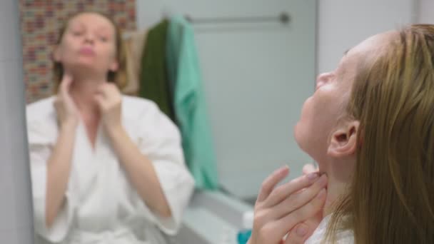 Face care koncept. Kvinna tillämpa kosmetiska lotion för att ta hand om huden i badrummet. Morgon hygien — Stockvideo