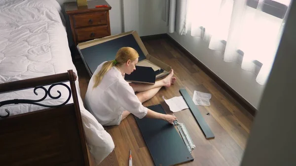Merakit perabotan di rumah, seorang ibu rumah tangga merakit meja komputer menggunakan peralatan tangan . — Stok Foto