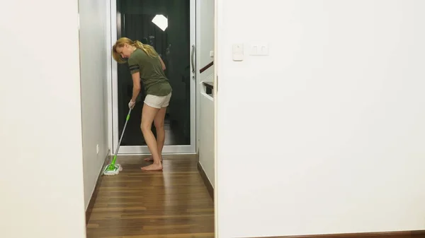 Mujer joven limpiando el dormitorio con productos y equipos de limpieza, concepto de trabajo doméstico — Foto de Stock