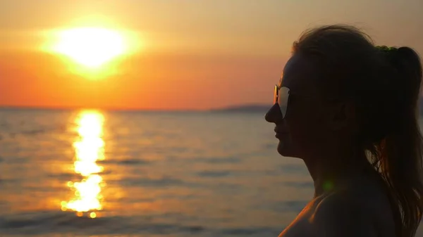 Hermoso atardecer soleado en el mar. vista a través de gafas de sol. mujer en gafas de sol mira la puesta de sol en el mar — Foto de Stock