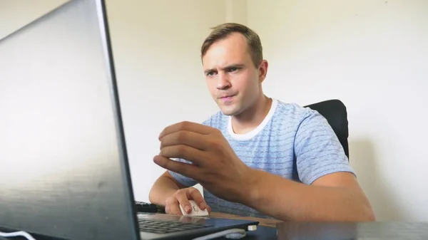 Um homem sentado em uma mesa em casa, trabalhando em casa laptop . — Fotografia de Stock