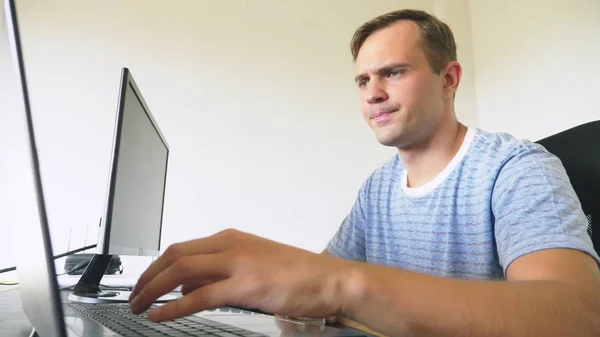 Un homme assis à un bureau à la maison, travaillant à la maison ordinateur et ordinateur portable . — Photo