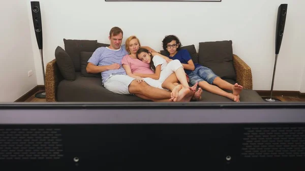 Encantadora família, mãe, pai, filha e filho estão assistindo TV na sala de estar juntos — Fotografia de Stock