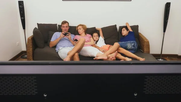 Charmante famille, maman, papa, fille et fils regardent ensemble la télévision dans le salon — Photo