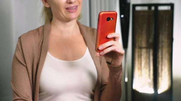 woman flirts talking on video communication from her smartphone. A woman sends a kiss online during a video call using a smartphone.