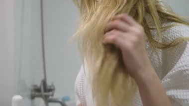 saç sağlığı, saç kaybı kavramı. Onun sarışın penye kadın banyoda kuru saçlar zarar