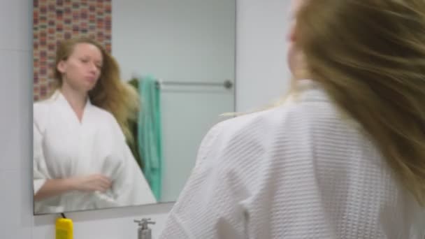 Salud del cabello, concepto de pérdida de cabello. Mujer peinando su cabello rubio seco dañado en el baño — Vídeo de stock