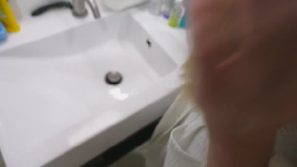 Salud del cabello, concepto de pérdida de cabello. Mujer peinando su cabello rubio seco dañado en el baño — Vídeo de stock
