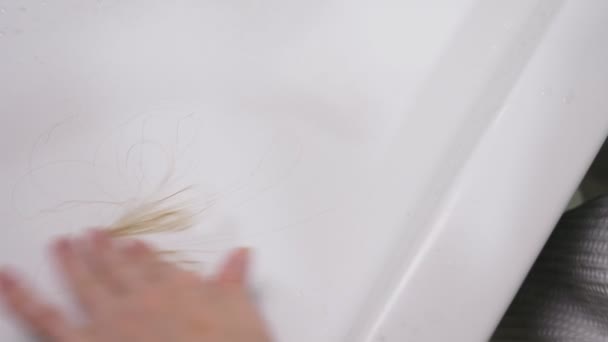 Salud del cabello, concepto de pérdida de cabello. Mujer peinando su cabello rubio seco dañado en el baño — Vídeo de stock