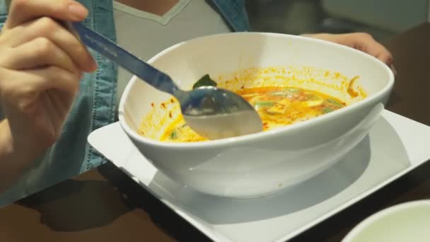 La sopa de camarones es un plato tailandés con un sabor agrio y picante. El hombre se come a Tom Yam en una mesa en un restaurante. Primer plano. concepto de turismo turístico — Vídeos de Stock