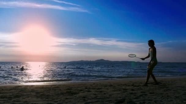 Silhuetter. personer spela badminton på stranden vid solnedgången. — Stockvideo