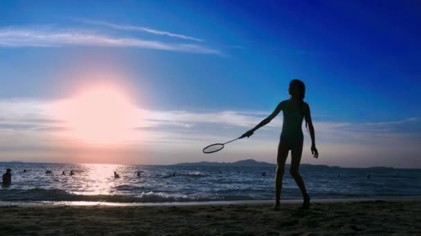 Silhouettes. les gens jouent au badminton sur la plage au coucher du soleil . — Video