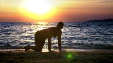 Oynak yakışıklı olan fitness, deniz kıyısı karşı harika bir gün batımı zemin üzerinde yapıyor şort.