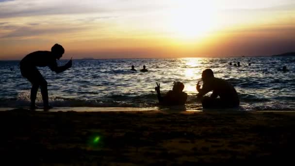 Un gruppo di giovani irriconoscibili viene fotografato in mare sullo sfondo del tramonto . — Video Stock