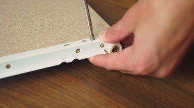 Genç bir adam bağımsız olarak mobilya evinin oturma odasında toplar. Bir adam bilgisayar masası toplar.