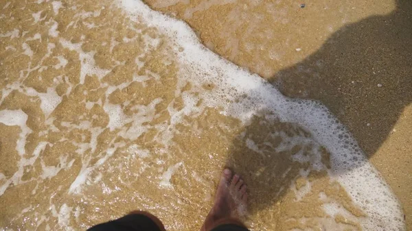 Мужские ноги на морском песке и волнах, Отдых на берегу океана, Летние каникулы . — стоковое фото